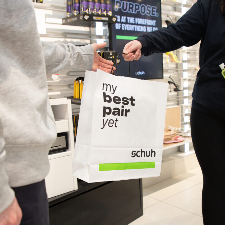 Shopper exchanging schuh bag in store with colleague 